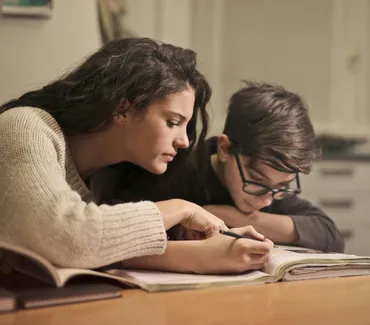 A tutor assisting a student with ADHD, both focused on a task at a desk, showcasing specialized support for executive functioning.