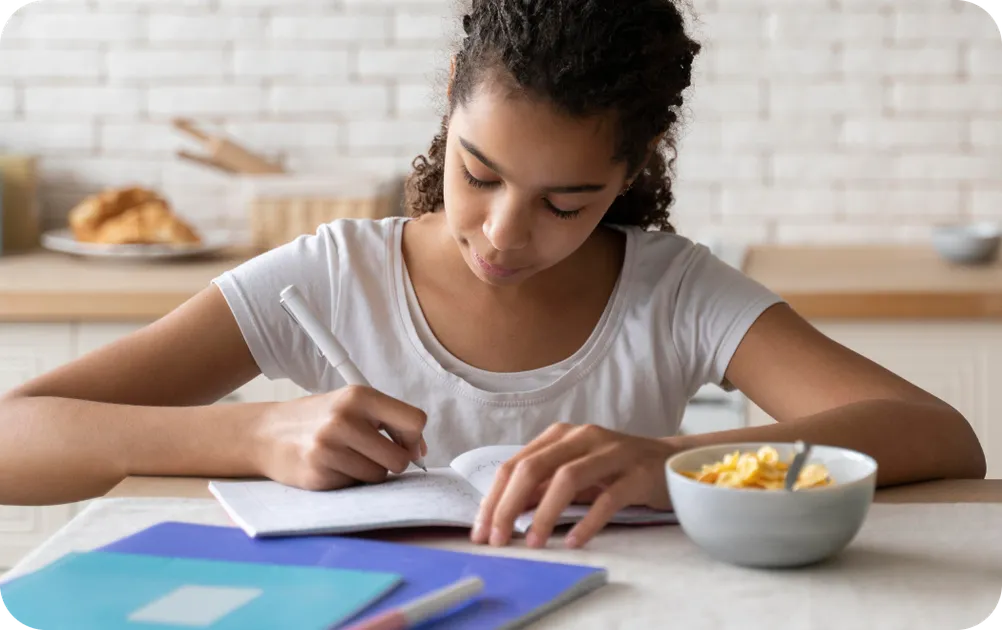 Teenage girl studying at desk with books and laptop