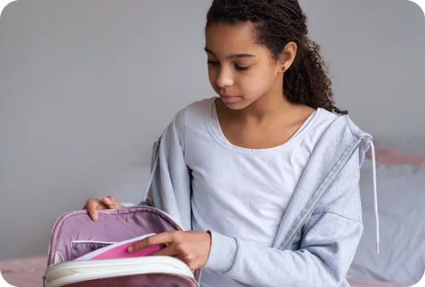 Teenage girl unpacking her bag, ready to study at her desk