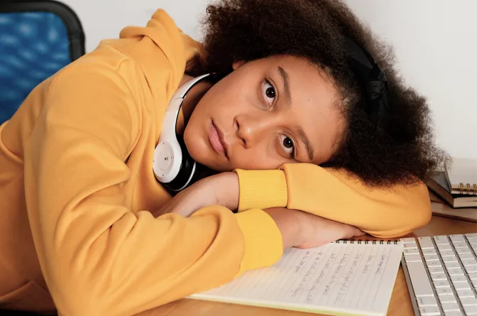 Student with inattentive ADHD resting head on desk feeling overwhelmed by schoolwork
