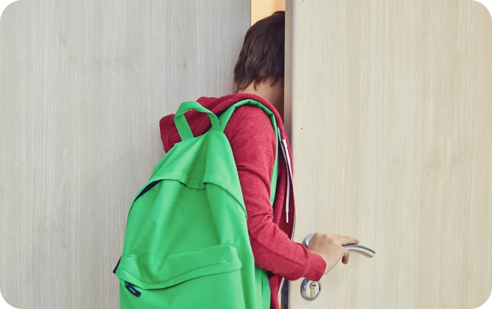 Teenage boy with green backpack walking out the door, leaving late for school