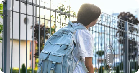 Back view of a boy with backpack walking away, representing leaving for school
