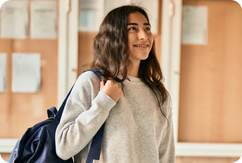 Cheerful teenage girl with backpack ready to leave for school