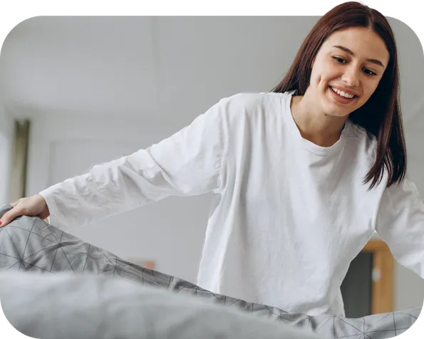 Teenage girl pulling her duvet to make her bed