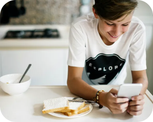 Boy using a smartphone at the breakfast table