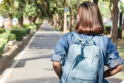 Teenage girl carrying her backpack and walking outdoors to school