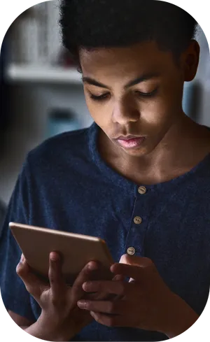 Male teenager staring at his ipad in the dark. The phone is illuminating his face.